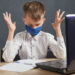 Social distance, self-isolation, online education concept. Boy in mask studying homework math during online lesson at home.