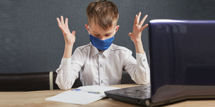 Social distance, self-isolation, online education concept. Boy in mask studying homework math during online lesson at home.